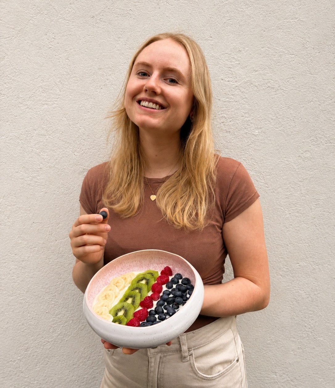 Jule Drössler hält eine Schale mit Joghurt, Banane, Kiwi, Himbeeren und Heidelbeeren